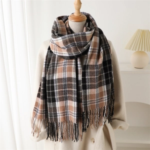 Detailed close-up of brown and black plaid scarf with fringe on a wooden neck mannequin