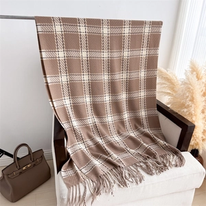 Détail d'une écharpe à carreaux douce avec des franges marron et beige sur un fauteuil