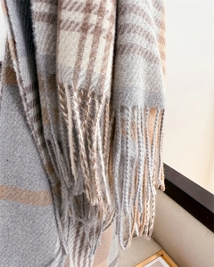 Detail view of plaid scarf fringe and soft twill weave texture in brown and grey