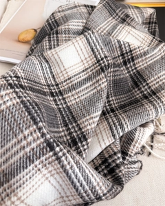 Gros plan d'une écharpe tissée à carreaux gris et beige avec des détails à franges
