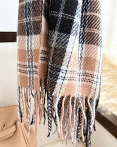 Close-up of fringe details and brown plaid pattern on a soft winter cashmere-like scarf