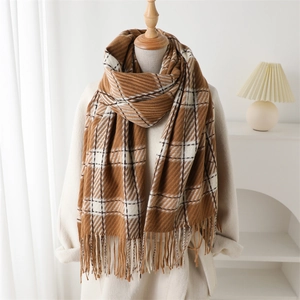 Vue détaillée d'une écharpe à carreaux marron et blanc avec franges sur un manteau crème