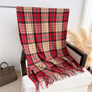 Macro detail of classic red and black tartan scarf with soft handmade fringe tassels