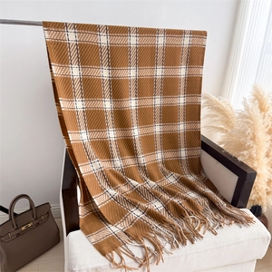 Détail d'une écharpe à carreaux en cachemire avec franges sur une chaise