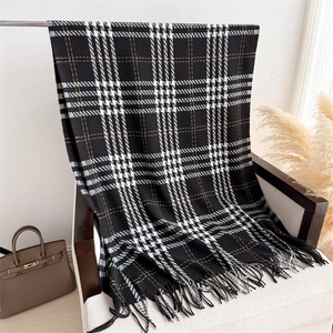 Detail view of black and white houndstooth scarf with brown stripes and fringe tassels