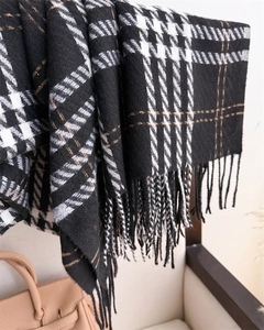 Detail of black and white houndstooth scarf with gold thread accents and soft fringe edges