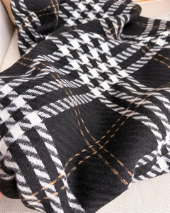 Detail of houndstooth scarf showing premium soft knit texture and woven bronze accent lines