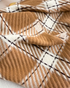 Détail d'une écharpe à carreaux en faux cachemire avec texture tricotée douce et franges