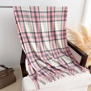 Detail of soft pink and black plaid cashmere shawl with tassels on a chair