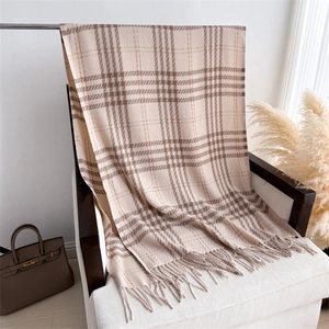 Detail of elegant beige and brown plaid cashmere-like scarf with fringe on a white chair