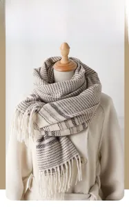 Detail of warm winter scarf with khaki geometric patterns and elegant long tassels