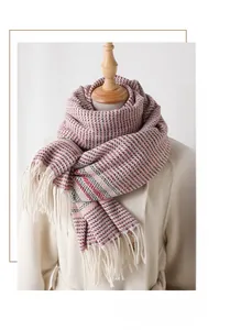 Detail of knit scarf with red and grey geometric pattern and long cream fringes