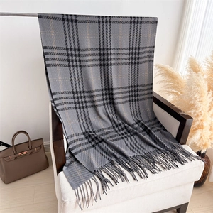 Detail shot of grey houndstooth patterned scarf with fringe edge on white armchair