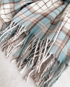Detailed view of plaid scarf fringe and soft faux cashmere texture in brown and beige