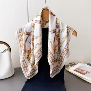 Elegant silk scarf with equestrian chain print tied to a chic black sweater on a hanger