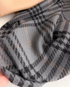 Macro detail of houndstooth scarf fabric with subtle gold metallic threads and soft texture