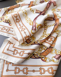 Detail of silk-like satin scarf with elegant equestrian chain and buckle print patterns