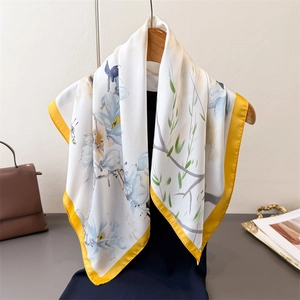 Elegante sciarpa in seta con stampa di magnolia e bordo giallo senape su stampella