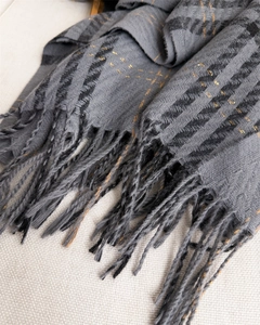 Detailed macro shot of grey plaid scarf texture featuring golden metallic thread accents