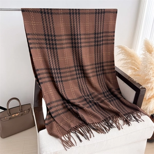 Detailed view of the thick checkered cashmere scarf with long tassels draped on a chair