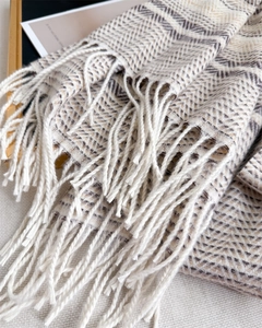 Close-up of geometric weave cashmere-like scarf with long fringe and classic herringbone pattern