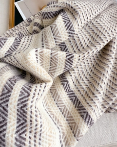 Detailed close-up of geometric zigzag patterned cashmere-feel knit shawl with soft texture
