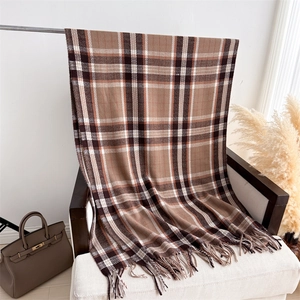 Classic brown plaid scarf draped on a chair featuring soft cashmere-like texture and fringe