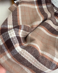 Detail view of classic brown plaid scarf featuring thick woven texture and tassels