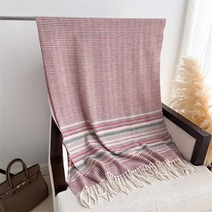Detail of pink and grey checkered knit scarf showing soft texture and fringe edges