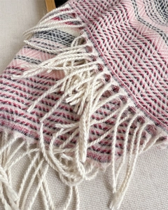 Detail of soft plaid scarf with pink and black herringbone pattern and woven tassels