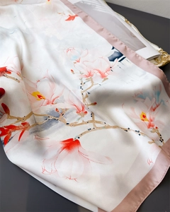 Dettaglio di sciarpa in seta con stampa di magnolia e bordo rosa su tessuto bianco