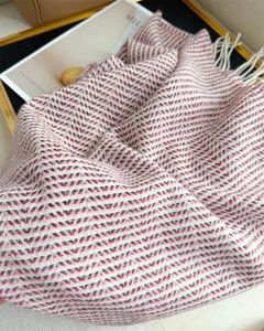 Close-up of winter cashmere-feel scarf featuring red herringbone pattern and white tassels