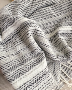 Close-up of navy and cream herringbone cashmere-feel scarf with elegant fringe detail