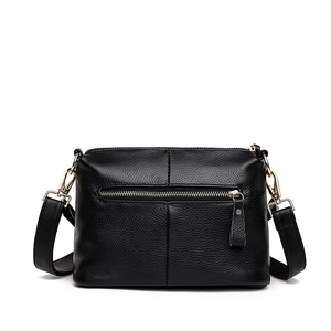 Minimalist black leather tote bag with lychee texture and adjustable strap on white background