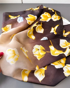 Dettaglio di un elegante foulard in seta con stampe di tulipani gialli e sfumature marroni