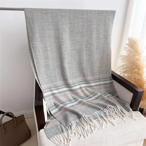 Detailed view of herringbone plaid scarf with soft white tassels on a cozy armchair