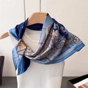 Detail of silk-like paisley scarf draped on a wooden hanger with light blue accents