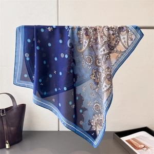 Detail of silk-like paisley square scarf showing refined rolled edges and smooth texture