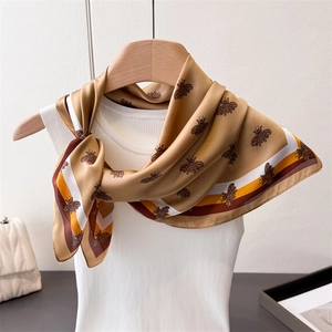 Detailed view of champagne silk scarf featuring realistic bee print and striped edges