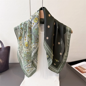 Elegant paisley print silk scarf with green daisy pattern draped on a hanger