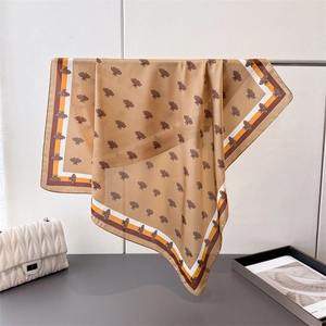 Detailed view of ginger silk scarf with bee print and striped edges draped elegantly
