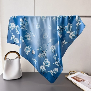 Dettaglio di sciarpa in seta con elegante stampa floreale blu e trama in raso