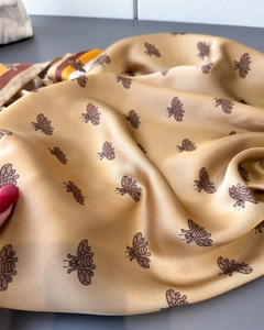 Detailed view of champagne gold satin scarf with elegant bee print and smooth texture