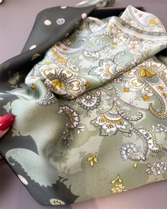 Detailed macro view of soft paisley silk scarf texture and elegant drape in sage green