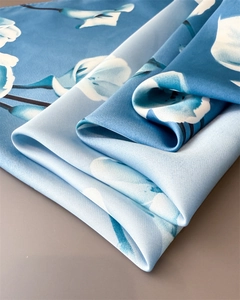 Dettaglio di un foulard in seta sfumata blu navy con eleganti motivi floreali bianchi