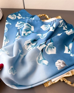Dettaglio della trama del foulard di seta blu con motivi floreali e finitura lucida