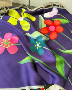 Gros plan du motif floral vibrant sur le tissu en soie violet foncé de ce foulard