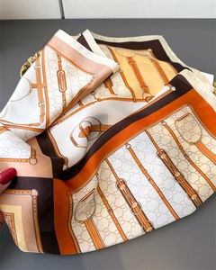 Detailed macro view of vintage silk scarf featuring equestrian chain motifs and metal buckles