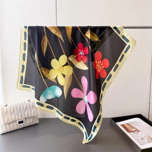 Détail de l'imprimé floral vif sur un foulard en satin de soie avec des feuilles dorées