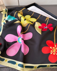 Détail d'un foulard en soie aux imprimés floraux vifs et bordure géométrique chic